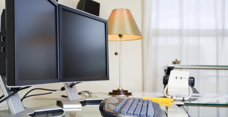 Desk in home office with dual monitors and keyboard